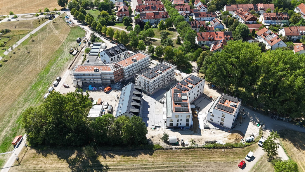 The image shows a newly constructed, multi-story residential building surrounded by trees and a rural landscape.

KI-generierte Inhalte können fehlerhaft sein.